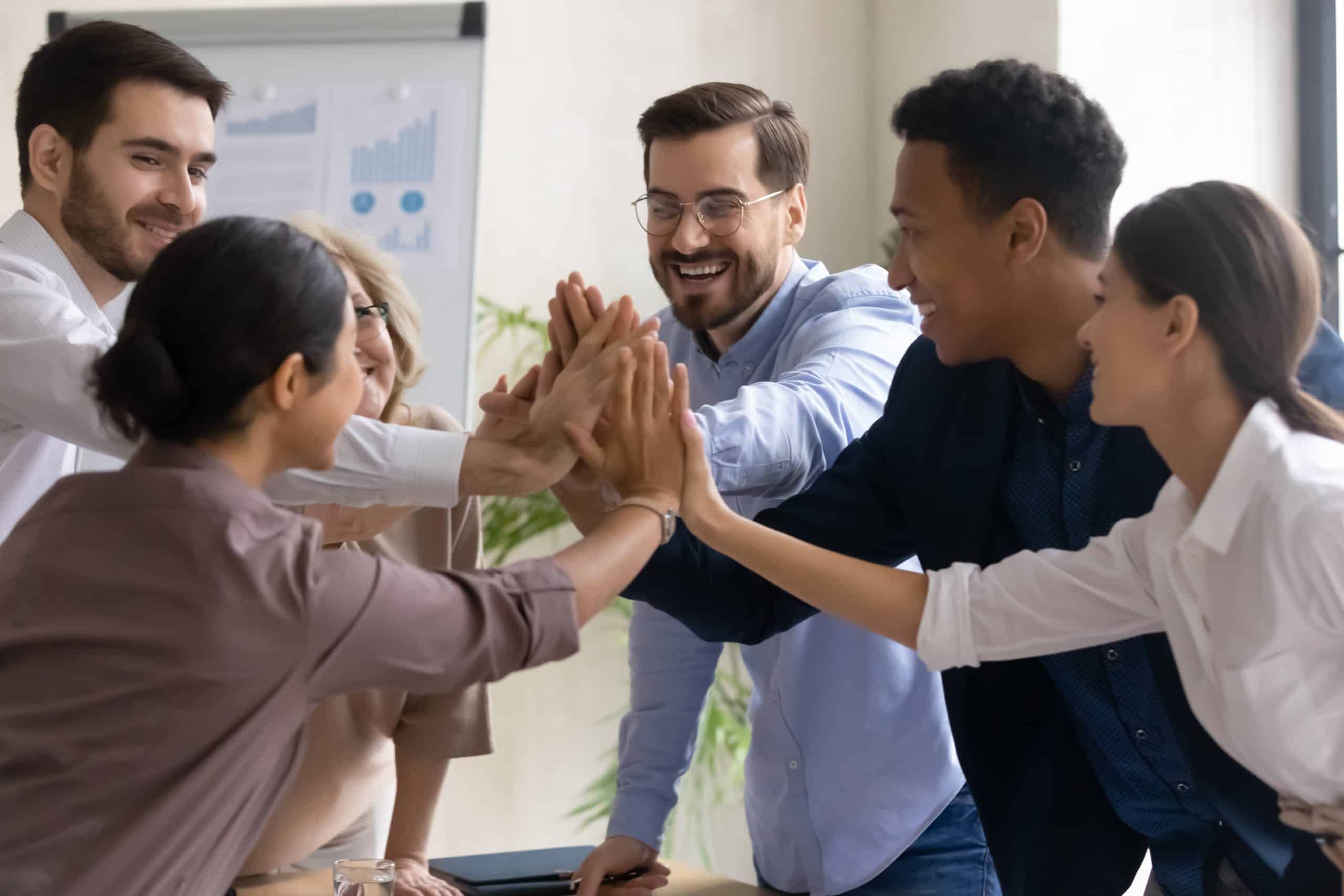 Diverse workers coach giving high five at company meeting.