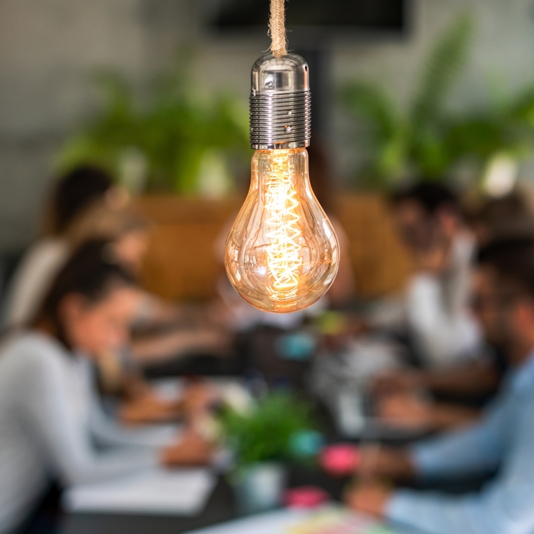 Young business people are discussing together a new startup project. A glowing light bulb as a new idea.
