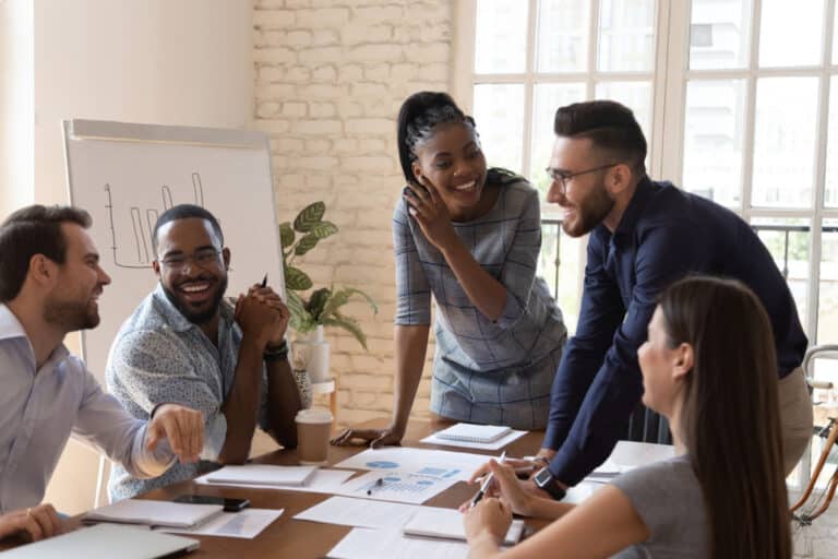 group of five people in business attire around a table working and smiling