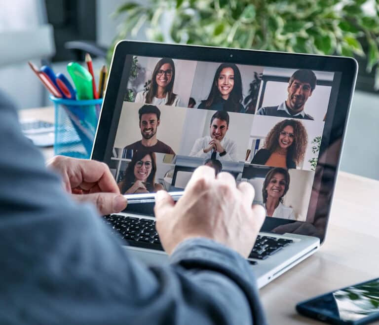close up of person's hands sitting at laptop of video call with employees