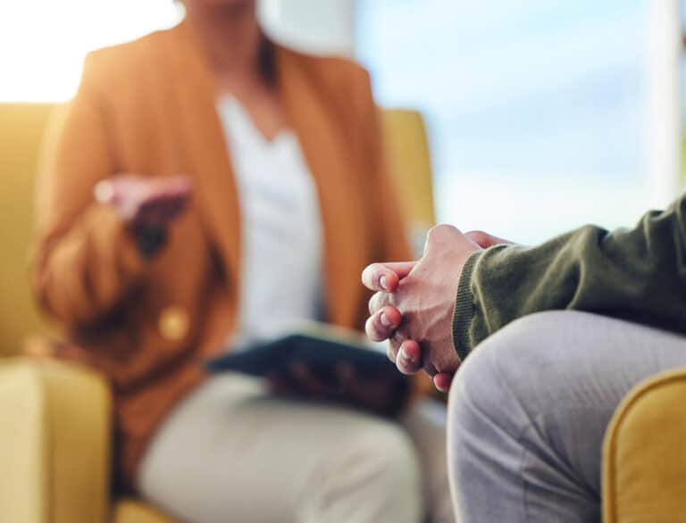 close up of hands together sitting across from person with book open and hand gesturing