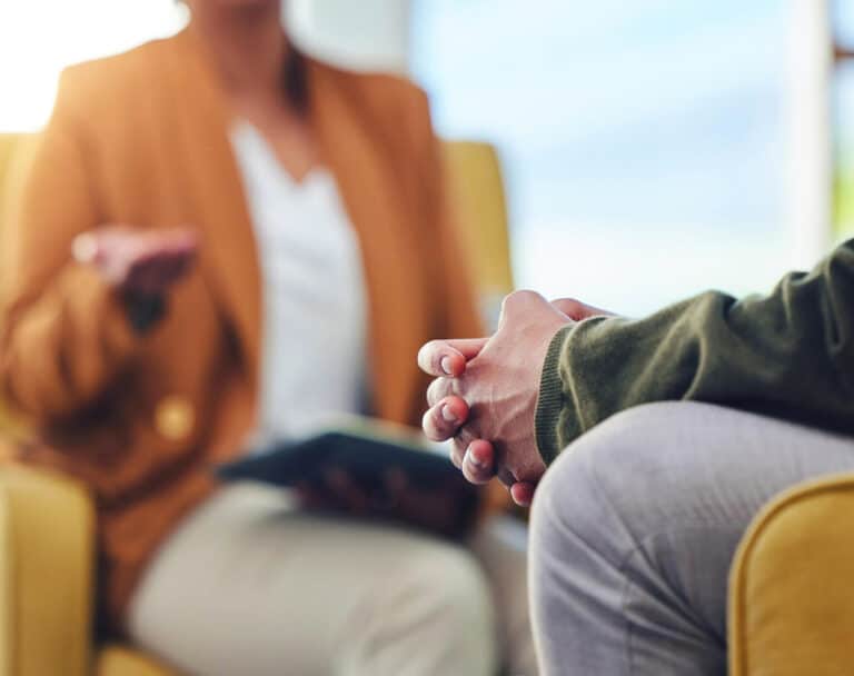 close up of hands together sitting across from person with book open and hand gesturing