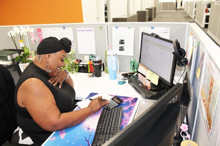 Payroll specialist sitting at her desk typing into a calculator