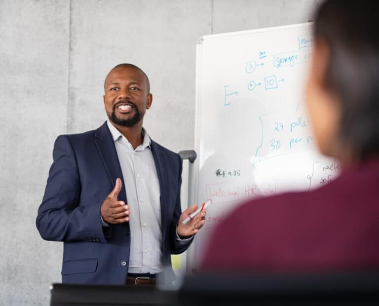 man standing talking with his hands explaining with dry erase board