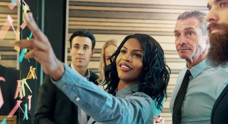 woman at wall with sticky notes explaining concept to other colleagues
