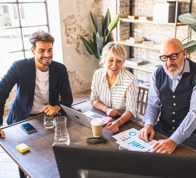 Mature male entrepreneur explaining to colleagues something on the screen in front of them