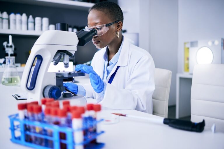 Science, laboratory and woman looking through a microscope.