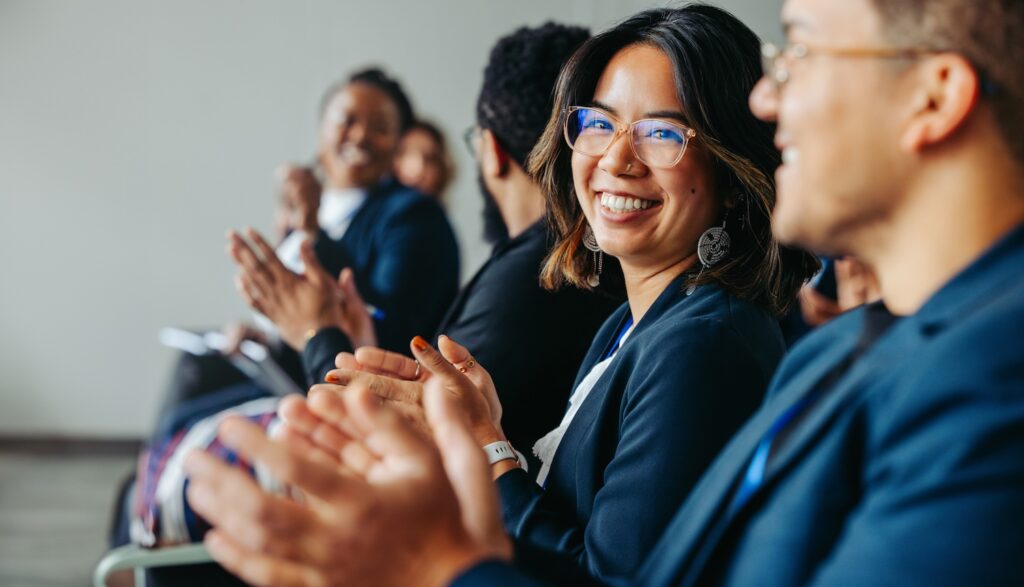 colleagues clapping and smiling happily during a business meeting.