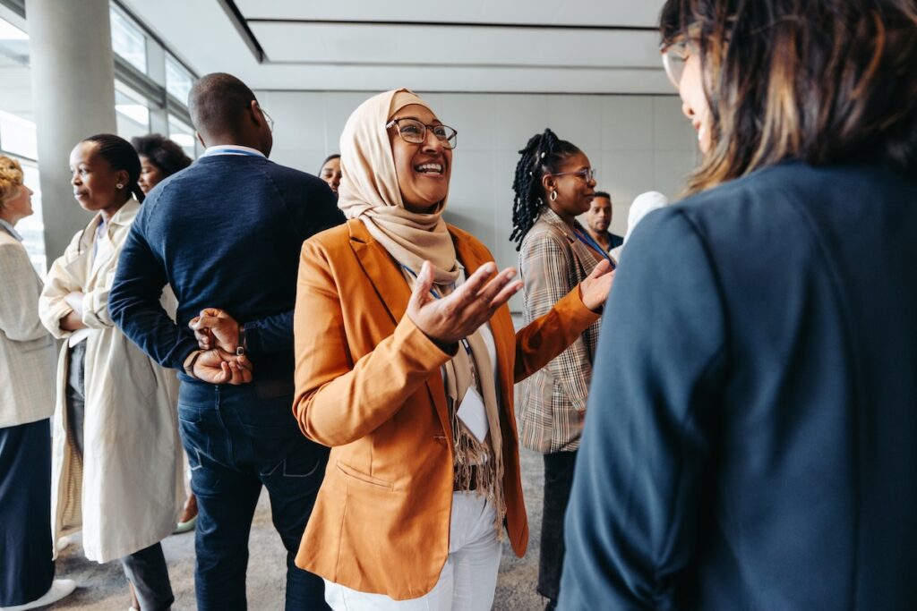 Smiling Muslim businesswoman sharing and talking with colleagues at a networking event.