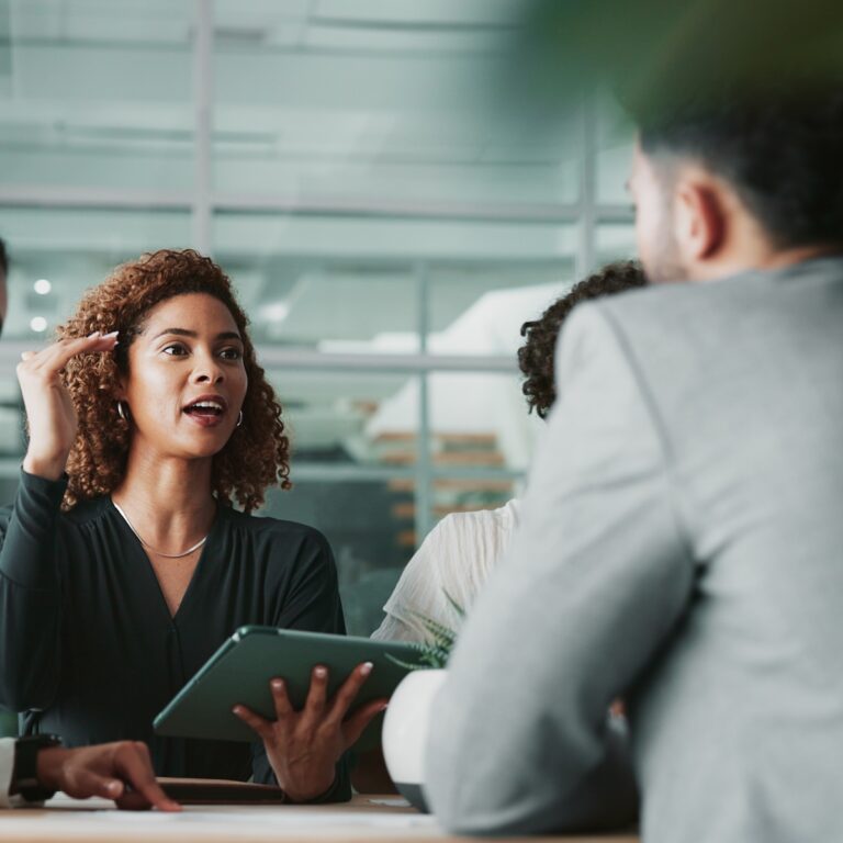 Woman holding a tablet at a meeting with a team