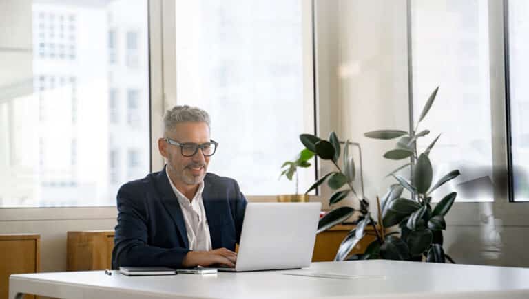 smiling-optimistic-mature-gray-haired-businessman-ceo-wearing-eyeglasses-using-laptop