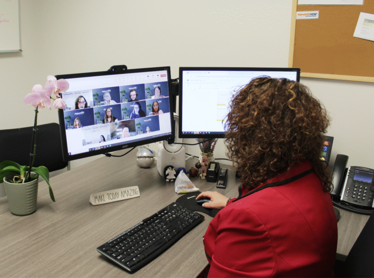 AlphaStaffHCM employee sitting at their computer on an online call with other colleagues.