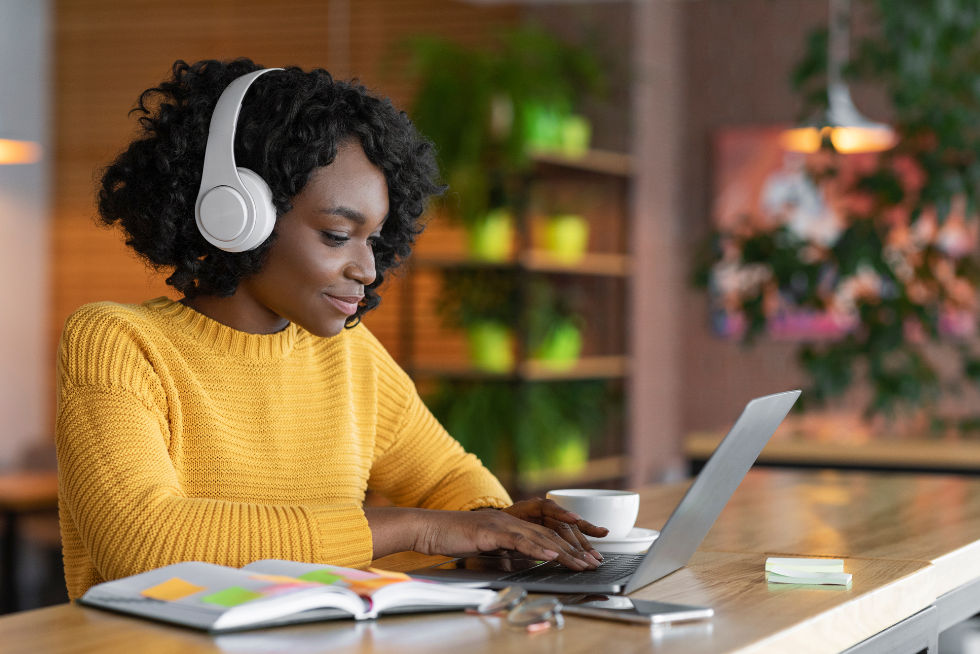 woman with headphones sitting typing on laptop