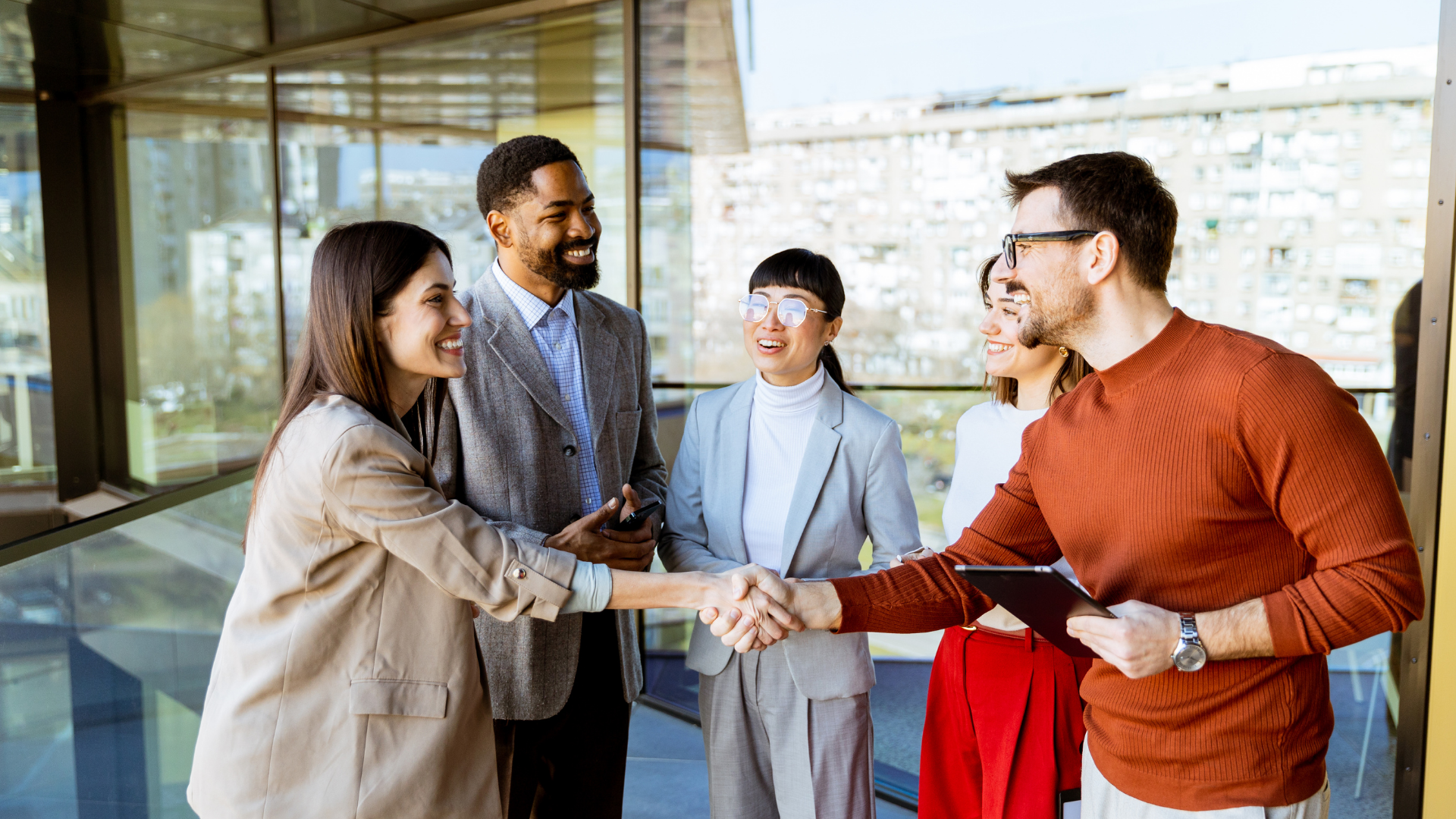 Group of 5 colleagues with different ethnicities speaking and shaking hands greeting each other