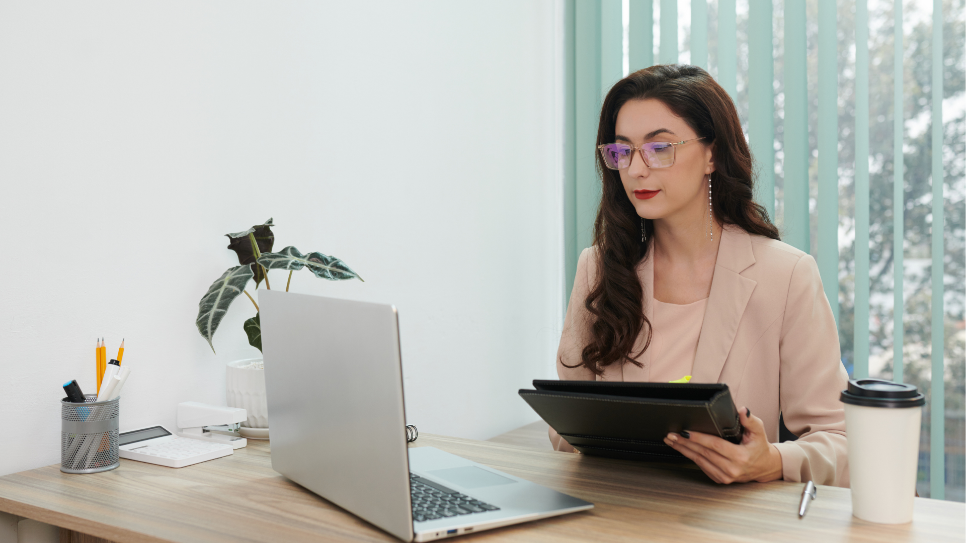 HR Professional with brown hair and eye glasses reviewing information on her laptop