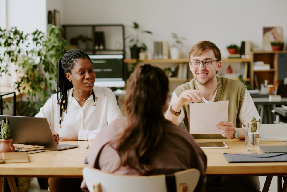 Photo of a woman and a man interviewing a candidate with their back facing us