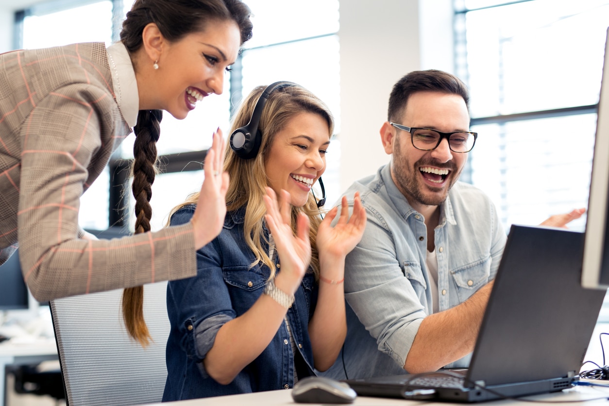 group of colleagues waving to someone in an online meeting on their laptop