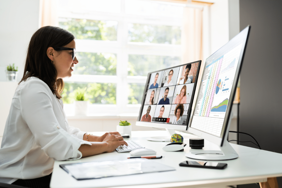 woman sitting in front of two computer screens on a meeting with other colleagues
