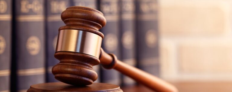 A picture of a Law Gavel with books on the background