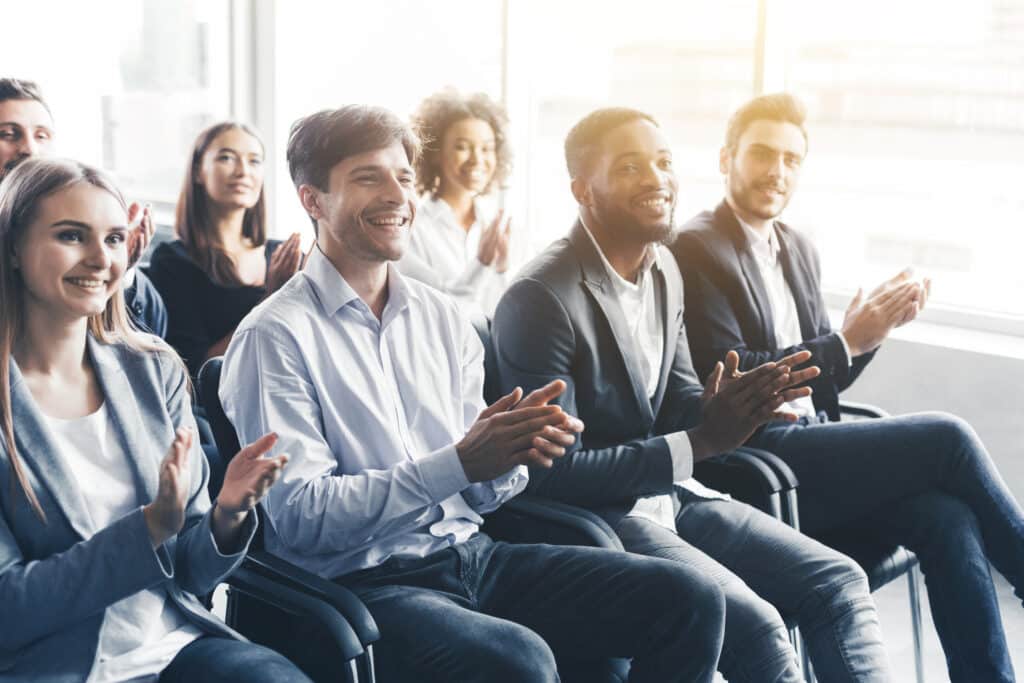 Happy diverse audience applauding at business training.