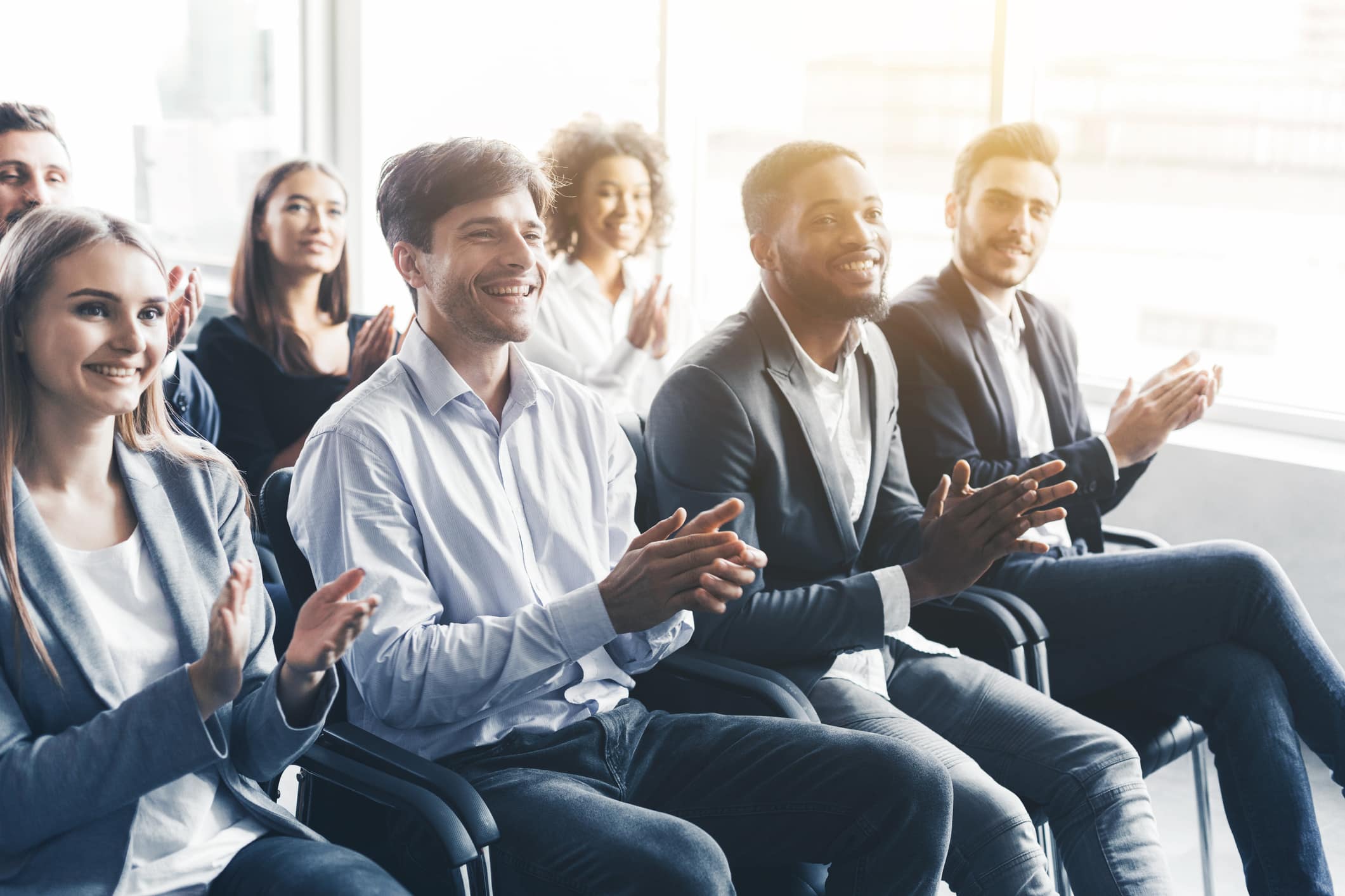 Happy diverse audience applauding at business training.